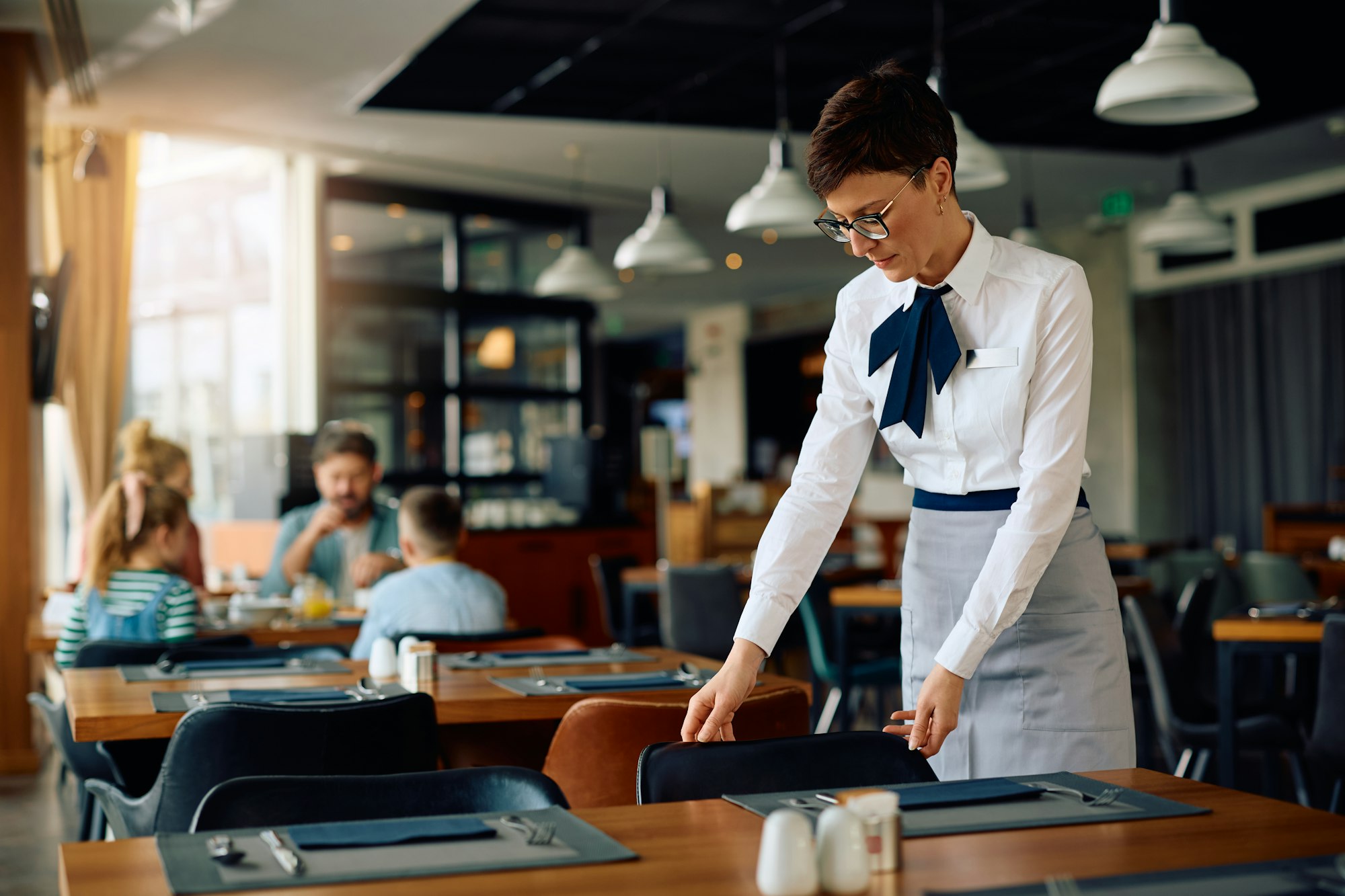 Hotel waitress setting the tables in a restaurant.